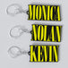 Three custom Nirvana keychains with yellow and black text, each with a different name: 'Monica', 'Nolan', and 'Kevin'.