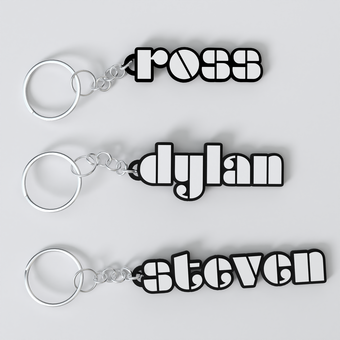 Three custom The Doors keychains with the names 'ross', 'dylan', and 'steven' printed on them, each keychain is black with a white outline of the name and a silver keyring.