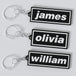 Three custom Oasis keychains with names 'James', 'Olivia', and 'William' displayed on a white background.