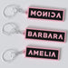 Black pink custom keychains with the names "MONICA", "BARBARA" AND "AMELIA".