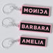 Black pink custom keychains with the names "MONICA", "BARBARA" AND "AMELIA".