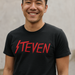 Man wearing a custom Slayer black t-shirt with red text 'STEVEN' against a neutral background