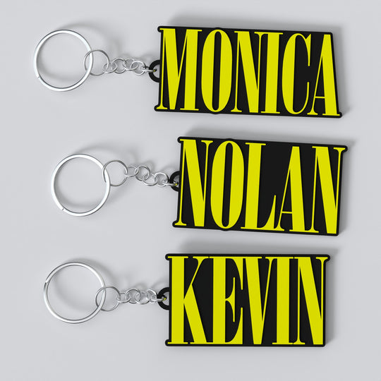 Three custom Nirvana keychains with yellow and black text, each with a different name: 'Monica', 'Nolan', and 'Kevin'.