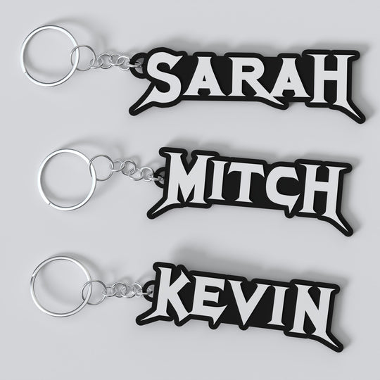 Three custom Megadeth keychains with the names 'Sarah', 'Mitch', and 'Kevin' printed on them, each keychain has a silver keyring and a chain link.