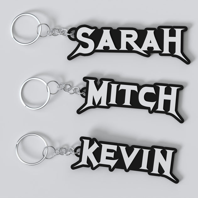 Three custom Megadeth keychains with the names 'Sarah', 'Mitch', and 'Kevin' printed on them, each keychain has a silver keyring and a chain link.