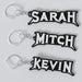 Three custom Megadeth keychains with the names 'Sarah', 'Mitch', and 'Kevin' printed on them, each keychain has a silver keyring and a chain link.