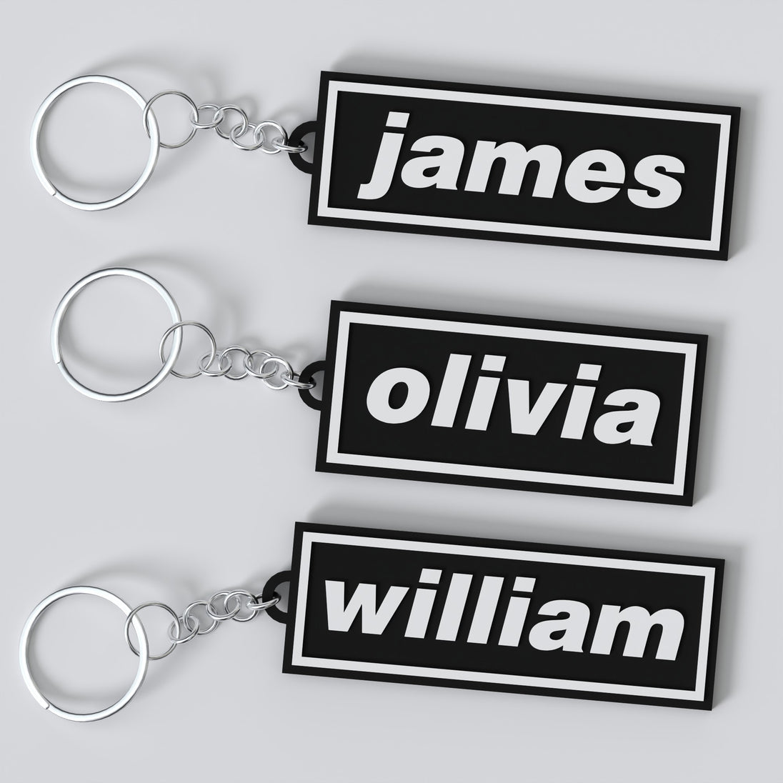 Three custom Oasis keychains with names 'James', 'Olivia', and 'William' displayed on a white background.