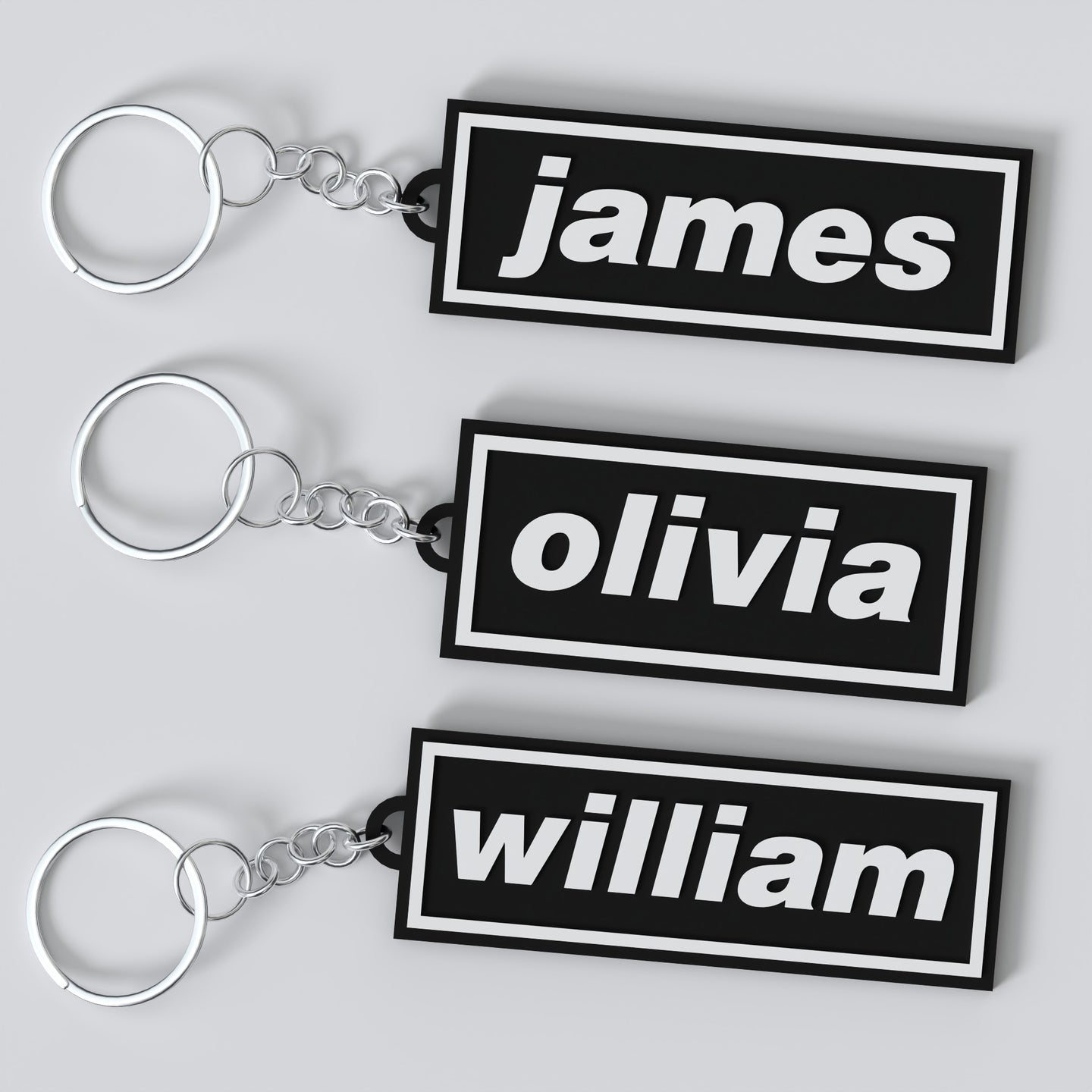 Three custom Oasis keychains with names 'James', 'Olivia', and 'William' displayed on a white background.