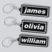 Three custom Oasis keychains with names 'James', 'Olivia', and 'William' displayed on a white background.