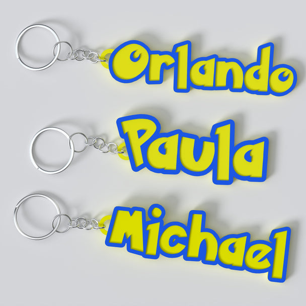Three Pokemon custom keychains with personalized text. The keychains are in blue, yellow, and white colors with the text 'ORLANDO', 'PAULA', and 'MICHAEL' respectively.